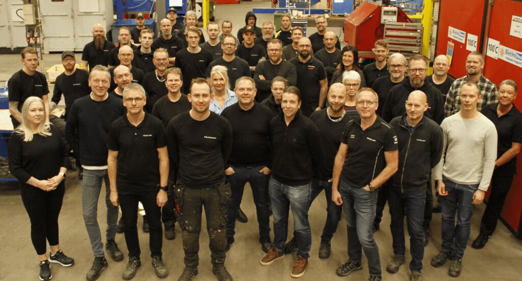 Stor gruppbild på UW-ELAST:s samtliga medarbetare i fabrikslokalen